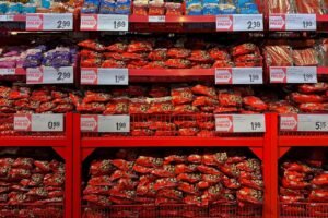 Vibrant assortment of candy bags in a supermarket with signs in Dutch promoting low prices.